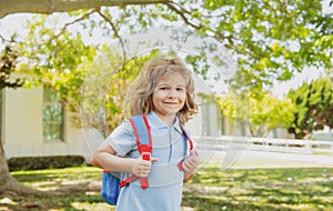 Kid with backpack going to school. Kids education concept. Child with rucksacks standing in the park near school. Pupils