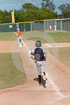Kid baseball player taking first base