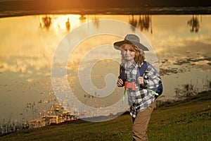 Kid with binoculars hiking at nature. Little explorer. Outdoor recreation and adventures with kids. Child tourist on