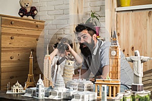 Kid with binoculars and his excited dad playing with paper models of world heritage sites, traveling around globe