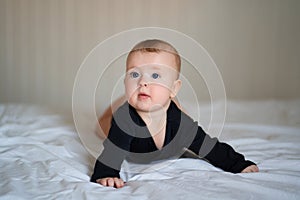 Kid in black clothes lying on paunch on white bed