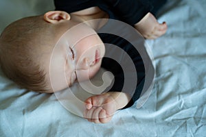 Kid in black clothes is sleeping on a white bed