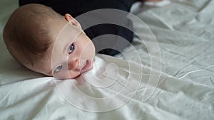 The kid in black lying on paunch on white bed