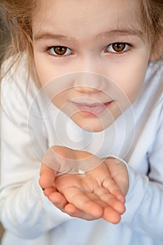 Kid blonde girl with fallen milk tooth in hand.