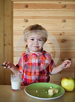 Kid or blonde happy boy eating apple.