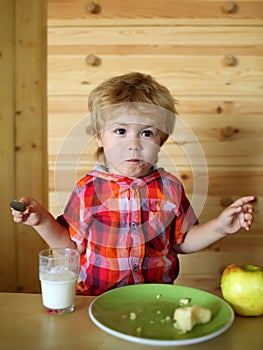 Kid or blonde happy boy eating apple.