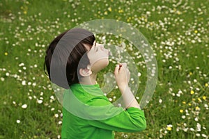 Kid blowing dandelion outdoors