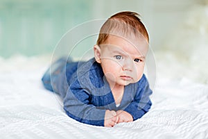 The kid in the blue jacket frowns lying on the bed