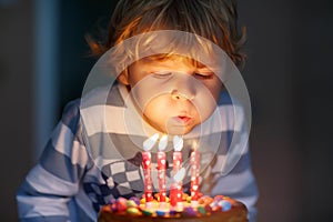 Kid boy celebrating his birthday and blowing candles on cake