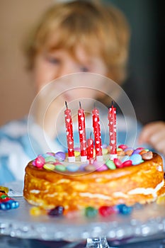 Kid boy celebrating his birthday and blowing candles on cake