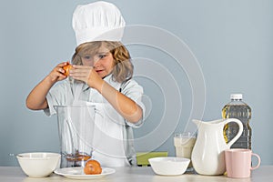 Kid boy in chef hat and apron cooking preparing meal. Little cook with vegetables at kitchen. Natural kids food.