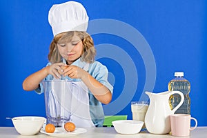 Kid boy in chef hat and apron cooking preparing meal. Little cook with vegetables at kitchen. Natural kids food.