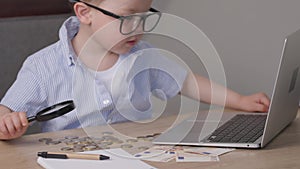 kid boy child in blue shirt typing laptop, money euro banknotes, coins on table