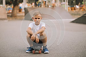 Kid boy child sitting on skateboard in a special area in skatepark and very angry or offended