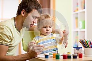 Kid boy and daddy paint together