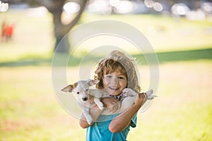 Kid boy with dog relaxing on nature. Lovely cute child embraces his pet doggy.