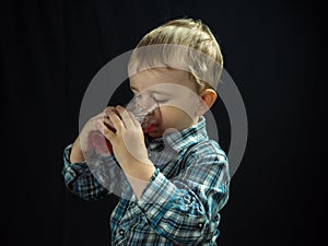 Kid boy drinking juice. Studio photo