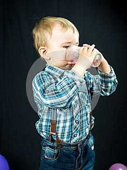 Kid boy drinking juice. Studio photo