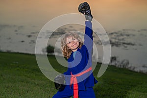 Kid boy exercising karate kataoutdoor. Sport karate kids. Little boy wearing kimono doing karate in park. Sport child