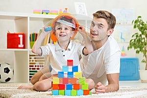 Kid boy and father play builders