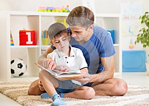 Kid boy and father read a book on floor indoors