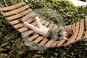 Kid, boy and happy with lying on hammock outdoor for fun to play, child development and growth. Children, holiday and