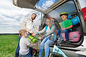 Kid boy helping his parents to load their car boot