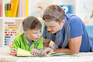 Kid boy and his father read a book on floor at home