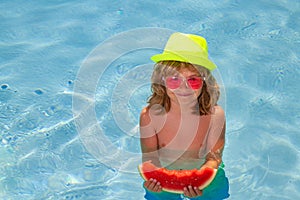 Kid boy hold watermelon relaxing in pool. Child swimming in water pool. Summer kids activity, watersports.