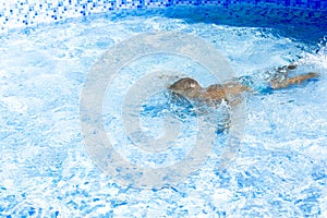 Kid boy holding breath underwater in sunny swimming pool. learning to swim