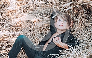 Kid boy holding gold leaf and lies on the hay. Sale for entire autumn collection, incredible discounts and wonderful