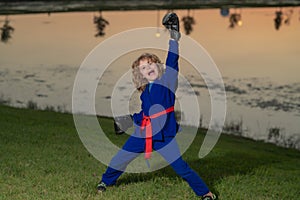 Kid boy in kimono practicing judo, taekwondo, jujitsu, kung-fu, jiu-jitsu, aikido outdoor. Sport karate kids. Little boy