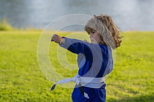 Kid boy in kimono practicing judo, taekwondo, jujitsu, kung-fu, jiu-jitsu, aikido outdoor. Sport karate kids. Little boy