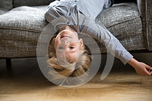 Kid boy lying upside down on sofa looking at camera