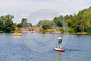 Kid boy paddling on sup board on a lake. Active child on modern trendy stand up paddle board. Summer outdoors vacations