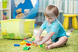 Kid boy playing with building blocks at home or kindergarten