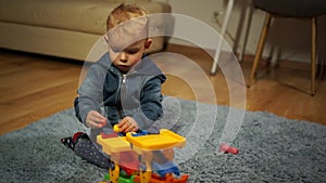 Kid boy playing with building blocks at home or kindergarten. Happy child is passionate about playing with plastic toy