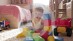 Kid boy playing with building blocks sitting on the floor at home. Child play on floor with educational toys.