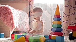 Kid boy playing with building blocks sitting on the floor at home. Child play on floor with educational toys.