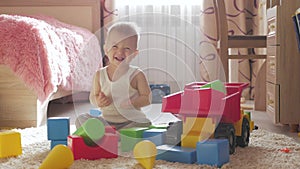 Kid boy playing with building blocks sitting on the floor at home. Child play on floor with educational toys.