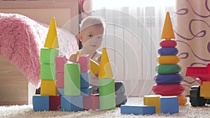 Kid boy playing with building blocks sitting on the floor at home. Child play on floor with educational toys.