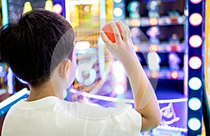 Kid boy playing a game of darts,holding a small plastic ball in his hands,aiming throwing at a target or a toy doll to knock it photo