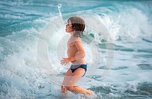 Kid boy playing and having fun on the beach on blue sea in summer. Blue ocean with wawes. Child boy swimming in sea. photo
