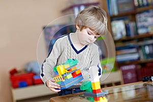 Kid boy playing with lots of colorful plastic blocks indoor