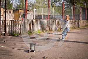 Kid boy playing skittles in the street. Russian game skittles. Wooden skittles. Outdoor activites with children. Child playing in