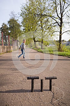 Kid boy playing skittles in the street. Russian game skittles. Wooden skittles. Outdoor activites with children. Child playing in