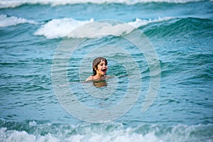 Kid boy playing and swimming in blue sea on summer. Blue ocean with wawes. Child boy swimming in sea. photo