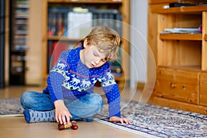 Kid boy playing with wooden balance toy at home