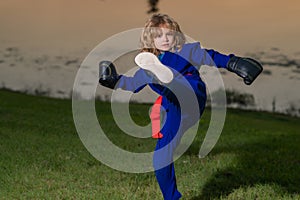 Kid boy practicing box outdoor. Sport karate kids. Little boy in kimono doing box in park. Child with boxing gloves