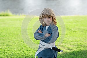 Kid boy practicing karate outdoor. Sport karate kids. Little boy wearing kimono doing karate in park. Child training box